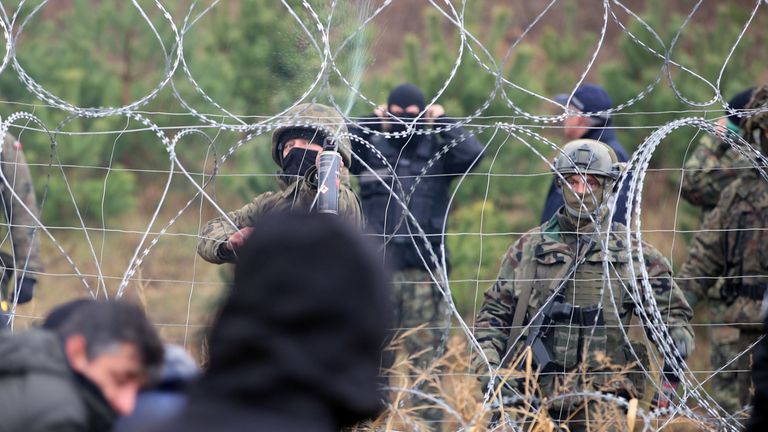 A Polish service member sprays liquid through a barbed wire fence as hundreds of migrants gather on the Belarusian-Polish border in an attempt to cross it in the Grodno region, Belarus November 8, 2021. Leonid Scheglov/BelTA/Handout via REUTERS ATTENTION EDITORS - THIS IMAGE HAS BEEN SUPPLIED BY A THIRD PARTY. NO RESALES. NO ARCHIVE. MANDATORY CREDIT.
