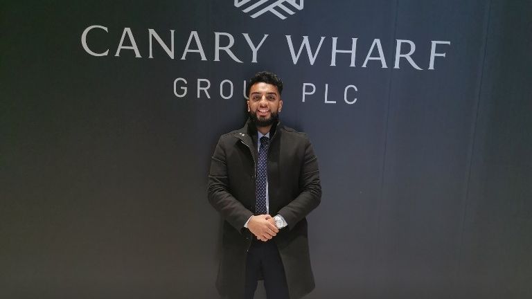 Haider Malik posing in front of Canary Wharf sign. He got the job