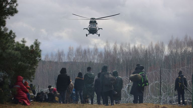 Migrants gather near a barbed wire fence in an attempt to cross the border with Poland in the Grodno region, Belarus November 8, 2021. Leonid Scheglov/BelTA/Handout via REUTERS ATTENTION EDITORS - THIS IMAGE HAS BEEN SUPPLIED BY A THIRD PARTY. NO RESALES. NO ARCHIVE. MANDATORY CREDIT.  