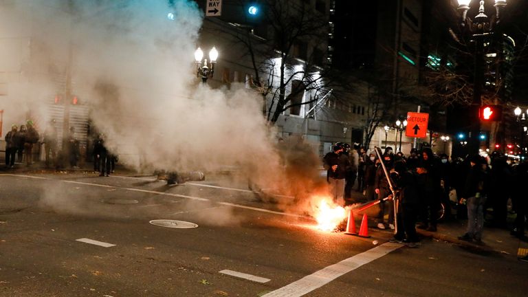 A small fire obscures the Justice Center after the full acquittal verdict of teenager Kyle Rittenhouse in his deadly shootings trial, in Portland