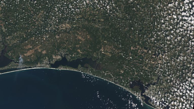 Pasir putih Pantai Pensacola menonjol dalam gambar Landsat 9 Florida Panhandle Amerika Serikat ini, dengan Kota Panama terlihat di bawah awan seperti popcorn.  Landsat dan satelit penginderaan jauh lainnya membantu melacak perubahan pada garis pantai AS, termasuk pembangunan perkotaan dan potensi dampak kenaikan permukaan laut.