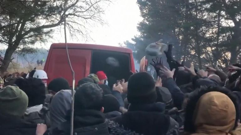 Video shows a group of people crowded around a van as packages are thrown out of it by what are said to be Belarus Red Cross.