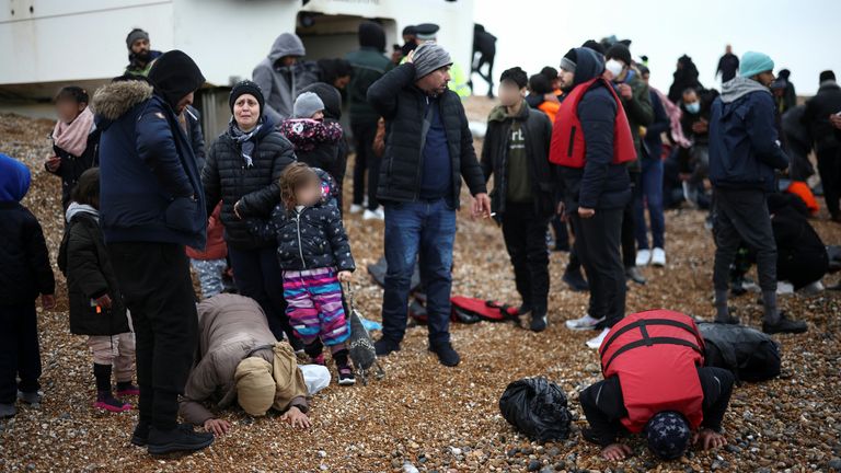 Migrants react as they gather on a beach after being brought ashore by a RNLI Lifeboat, after having crossed the channel, in Dungeness, Britain, November 24, 2021. REUTERS/Henry Nicholls
