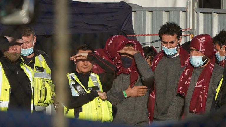 A group of people thought to be migrants wait in a holding area after being brought in to Dover