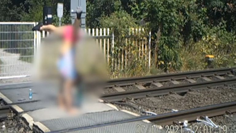 A teenage girl doing a handstand at a level crossing