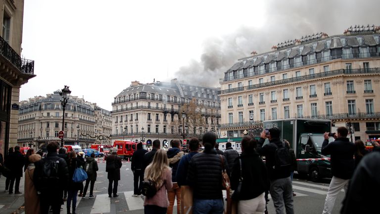 People watch as smoke billows from a building affected by a fire near the Opera Garnier in Paris