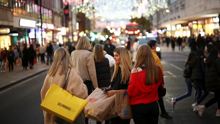 Des personnes avec des sacs à provisions marchent le long d'Oxford Street illuminée de lumières de Noël à Londres, en Grande-Bretagne, le 13 novembre 2021
