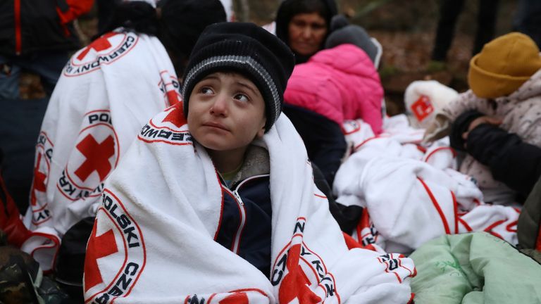 Migrants wrapped in blankets of Red Cross sit on the ground in a forest near the Polish-Belarusian border outside Narewka, Poland November 9, 2021. The group of migrants was later guided out of the forest by Polish border guards and taken to a detention centre. REUTERS/Kacper Pempel