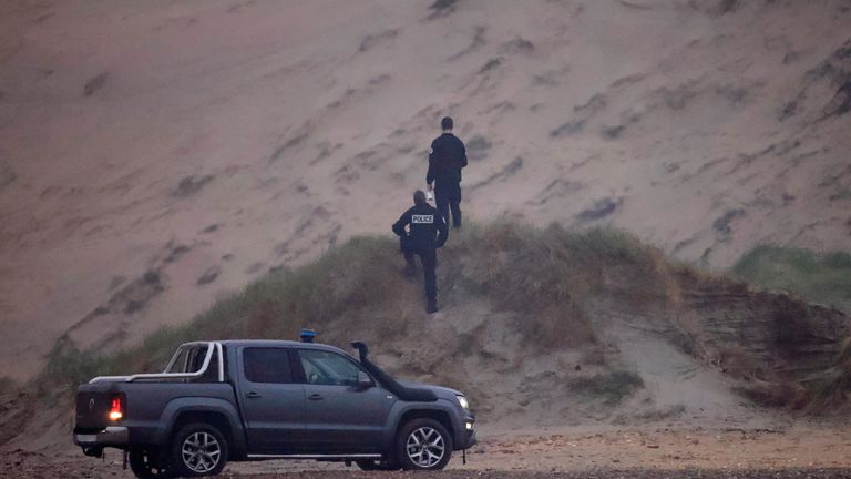 French police walk on the Slack dunes after a group of more than 40 migrants on an inflatable dinghy left the coast of northern France to cross the English Channel, near Wimereux, France, November 24, 2021. REUTERS/Gonzalo Fuentes
