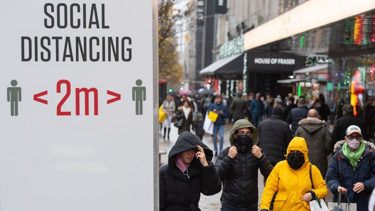 Shoppers pass social distancing signs on Oxford Street, in central London. -Christmas 2020 