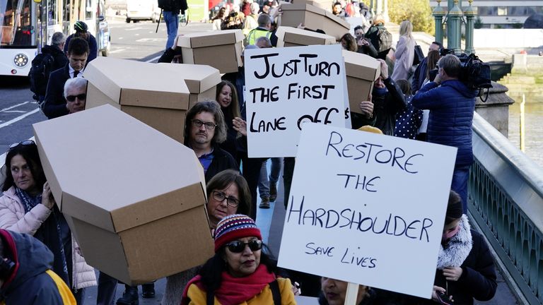 Protesters carry placards saying: "Just turn the first lane off" and "restore the hard shoulder save lives"