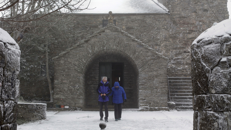 A couple leaves the chapel of the Holy Sepulchre of O Cebreiro, on November 27, 2021, in O Cebreiro, Pedrafita do Cebreiro, Lugo, Galicia (Spain). This snow is the result of the Arwen squall. Fourteen autonomous communities are at risk (yellow warning) or significant risk (orange warning) for snow, rain, wind or strong waves, as warned by the State Meteorological Agency (AEMET), which expects this storm to accentuate the storm affecting the northern half of the Peninsula. 27 NOVEMBER 2021;VITORI