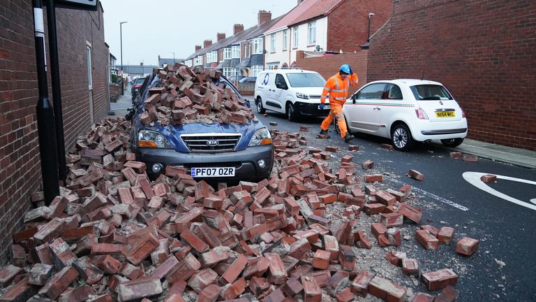Un homme met en sécurité la maçonnerie tombée d'une propriété, qui a endommagé une voiture à proximité, sur l'avenue Gloucester à Roker, Sunderland, après que des rafales de près de 100 milles à l'heure ont frappé certaines régions du Royaume-Uni pendant la tempête Arwen.  Photo date : samedi 27 novembre 2021.