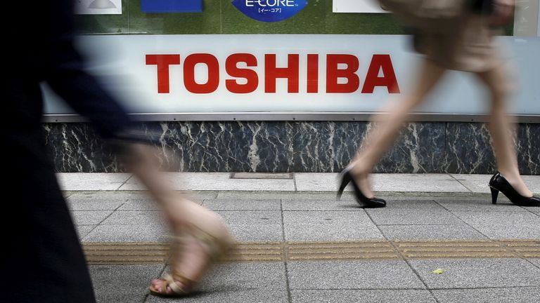 FILE PHOTO: Pedestrians walk past a logo of Toshiba Corp outside an electronics retailer in Tokyo September 14, 2015.
