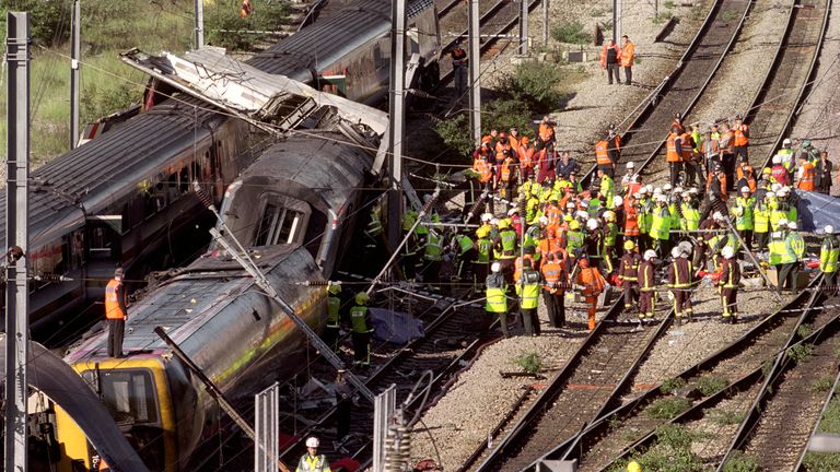 Rescue workers surround the wreckage of two trains which lie on rails in west London after a crash near Paddington Station. A number of passengers have died in the accident, and over a hundred  were injured when the two mainline trains collided in the morning rush hour.   * Carriages were set ablaze by the collision and derailment, and scores of passengers were still trapped  hours after the crash about two miles from Paddington main line station. 