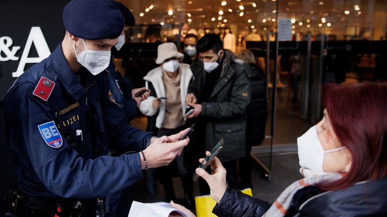 Police officers check the vaccination status of shoppers against the coronavirus disease (COVID-19) at the entrance of a store in Vienna, Austria