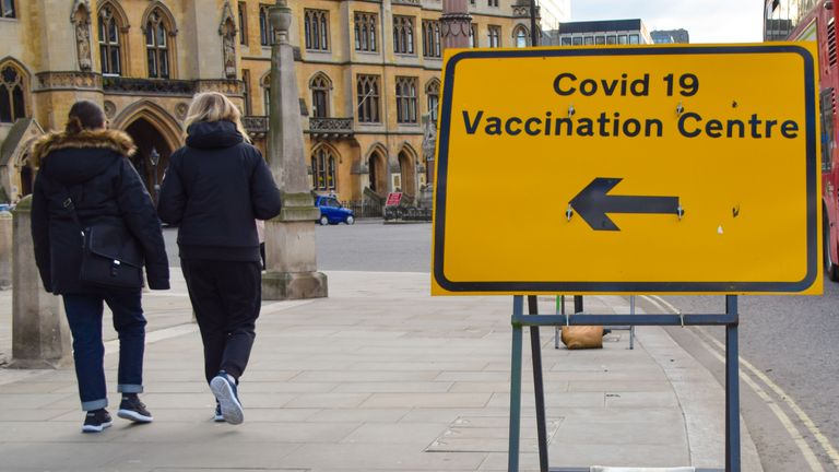 London, United Kingdom - March 19 2021: People walk past a Covid-19 Vaccination Centre sign outside Westminster Abbey.
