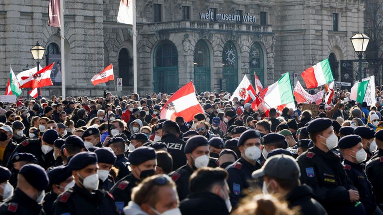 Police officers stand guard as demonstrators gather in the Austrian capital