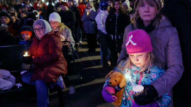A small child takes part in a candle light vigil in downtown Waukesha, Wis., Monday, Nov. 22, 2021 after an SUV plowed into a Sunday Christmas parade injuring dozens of people.  Five people were killed and 48 injured. (AP Photo/Jeffrey Phelps)
