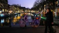 A woman crosses a canal in Amsterdam, the Netherlands on Saturday, Dec. 18, 2021.  Dutch government ministers are meeting Saturday to discuss advice from a panel of experts who are reportedly are advising a toughening of the partial lockdown that is already in place to combat COVID-19. (AP Photo/Peter Dejong)