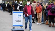 A man walks next to a queue of people waiting to receive COVID-19 vaccine and booster doses, as the spread of the coronavirus disease (COVID-19) continues, at a walk-in vaccination centre at Saint Thomas&#39; Hospital in London, Britain, December 14, 2021. REUTERS/Toby Melville  