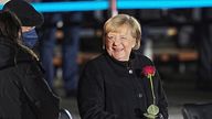 02 December 2021, Berlin: Chancellor Angela Merkel (CDU) laughs with a rose in her hand next to her husband, Joachim Sauer, after her farewell by the Bundeswehr. Chancellor Merkel is bid farewell with a Grand Taps ceremony at the Bendlerblock towards the end of her term in office after 16 years. 