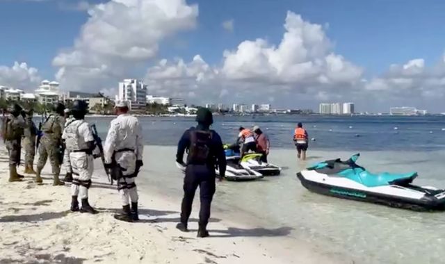 Tourists run for cover after gunmen on jet skis open fire on the beachfront of Cancun