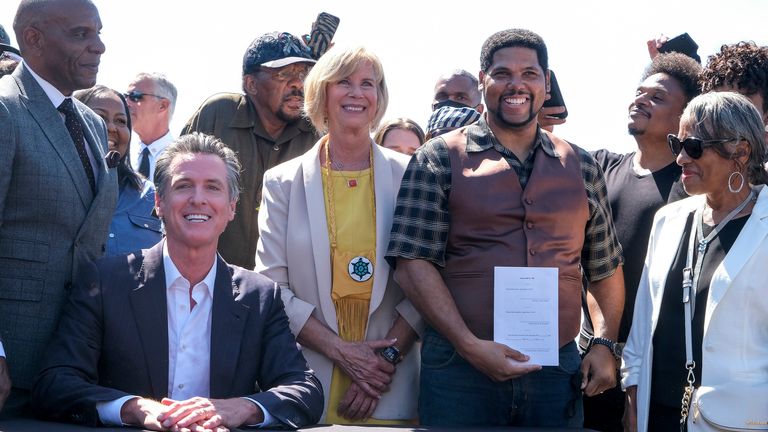 Anthony Bruce holds a bill ...Bruce...s Beach Bill... after California Gov. Gavin Newsom signed it that would help clear the way for the Los Angeles County to return a piece of Manhattan Beach coastline to the descendants of a Black family who had the land stripped away by the city nearly a century ago, Thursday, Sept. 30, 2021, in Manhattan Beach, Calif. (AP Photo/Ringo H.W. Chiu)..