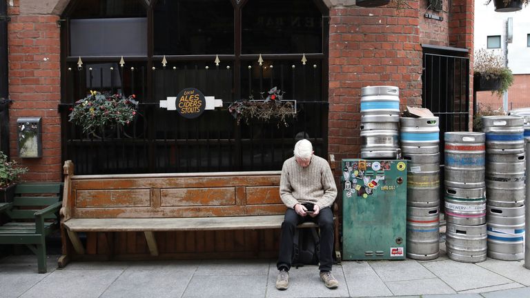 A man sits outside a closed bar in Belfast, Northern Ireland, Friday, Oct 16, 2020. Northern Ireland has brought in restrictions to try and &#39;circuit break&#39; the growing number of COVID-19 infections, they include -pubs closing from 1800, Friday, along with funerals and weddings limited to 25 people from for a period of 4 weeks. (AP Photo/Peter Morrison)