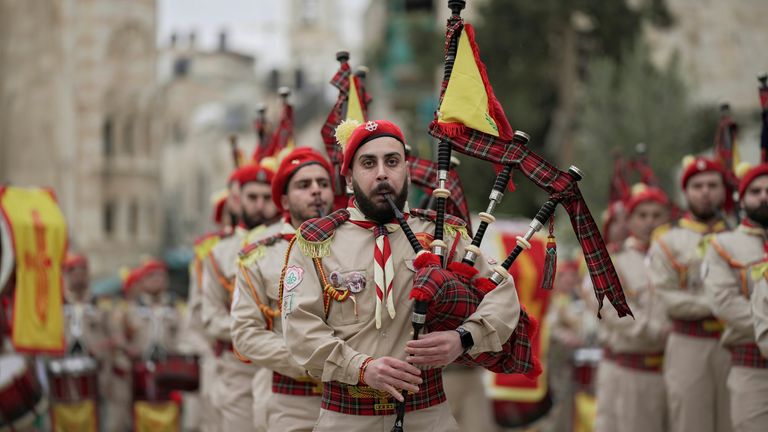 Palestinian scout bands parade through Manger Square at the Church of the Nativity,  traditionally believed to be the birthplace of Jesus Christ, during Christmas celebrations, in the West Bank city of Bethlehem, Friday, Dec. 24, 2021. The biblical town of Bethlehem is gearing up for its second straight Christmas Eve hit by the coronavirus with small crowds and gray, gloomy weather dampening celebrations Friday in the traditional birthplace of Jesus. (AP Photo/Majdi Mohammed)