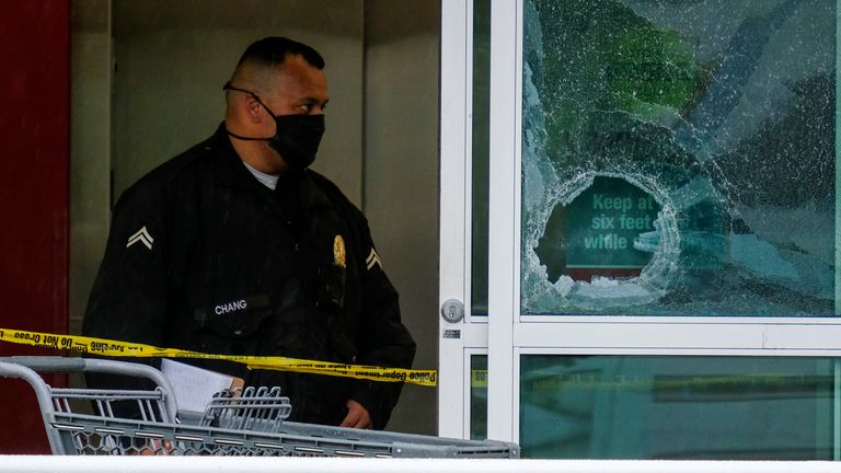 A police officer works behind a broken glass door at the scene of the shooting. Pic: AP
