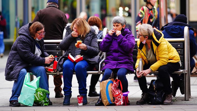 Christmas shoppers eat a meal on a bench in the centre of Cardiff, Wales, where people have been told to prepare for more restrictions in the coming weeks as the country faces an impending "tsunami" from the Omicron variant of Covid-19. Picture date: Thursday December 16, 2021.