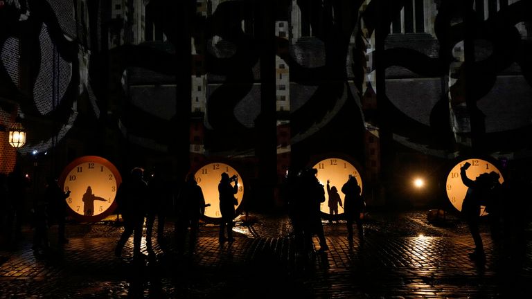 Visitors interact with and use their phones to document clock lighting on the &#34;Palace of Stardust&#34; light trail held for the Christmas season at Hampton Court Palace in south west London, Tuesday, Dec. 7, 2021. The River Thames-side palace was a home of King Henry VIII and last used as a royal residence more than 200 years ago