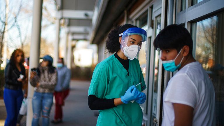 Maya Goode, a COVID-19 technician, left, talks with Sami Perez, 12, after he received a COVID-19 test outside Asthenis Pharmacy in Providence, Rhode Island. Pic: AP
