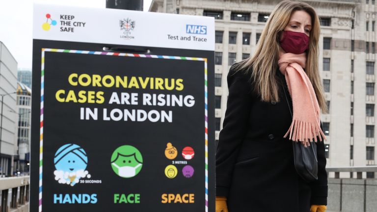 File foto seorang wanita berjalan melewati tanda informasi virus corona di Jembatan London.  Proporsi yang lebih besar dari orang kulit hitam dan Asia meninggal karena virus corona daripada orang kulit putih, meskipun jumlah kasus pada kelompok terakhir lebih tinggi, sebuah penelitian telah memperingatkan.