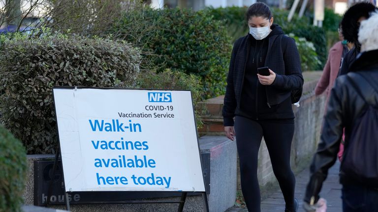 People walk past a COVID vaccination centre sign in London