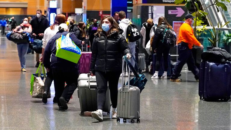 Travelers trek through Terminal E at Logan Airport, Tuesday, Dec. 21, 2021, in Boston. Public health officials are urging caution as the new omicron variant might become the dominant strain in the U.S. during the holiday break. (AP Photo/Charles Krupa)