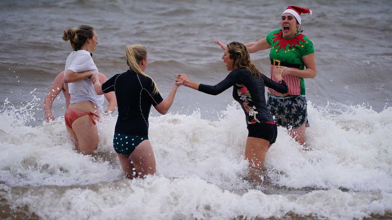 Swimmers in fancy dress take part in a Christmas Day dip at Exmouth, Devon. Picture date: Saturday December 25, 2021.