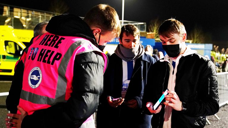 Fans show their COVID passes as they arrive for a Premier League match between Brighton and Wolves at the Amex stadium