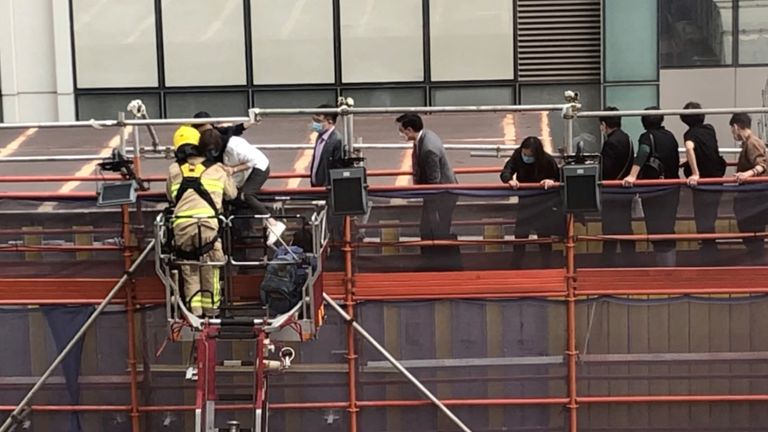 Firefighters use a crane to rescue people lined up on a roof after a fire broke out at the World Trade Centre in Hong Kong, China, December 15, 2021 in this still image obtained from a social media video. Wing Shun Kwok/via REUTERS THIS IMAGE HAS BEEN SUPPLIED BY A THIRD PARTY. MANDATORY CREDIT.
