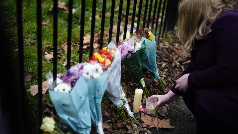 A woman lights a candle at the scene in Collingwood Road, Sutton, south London, where two sets of twin boys, aged three and four, died in a devastating house fire on Thursday. A 27-year-old woman has been arrested and held on suspicion of child neglect. Picture date: Friday December 17, 2021.
