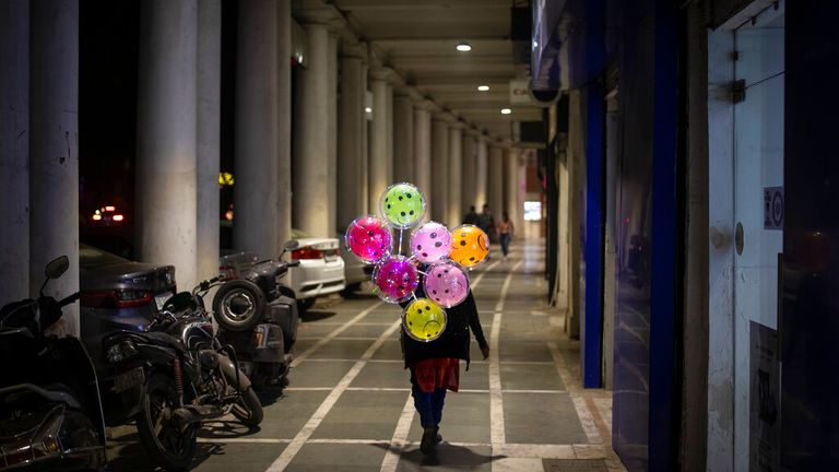 A balloon seller walks in a deserted shopping area in New Delhi 