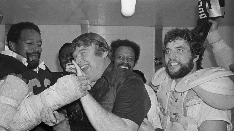 مربی جان مدن از اوکلند رایدرز در حالی که او و رایدرهایش در رختکن جشن می گیرند پس از شکست 24-7 پیتسبورگ در یک مسابقه قهرمانی AFC در یکشنبه 26 دسامبر 1976 در اوکلند، یک دوش کاملاً لباس دریافت می کند. 