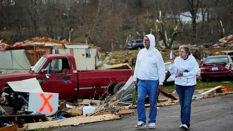 بیل مازلی با همسرش بانی راه می رود در حالی که دو اسلحه خود را حمل می کند، تنها وسایلی که پس از تخریب خانه آنها در ارلینگتون، کنتاکی، پیدا کرده است.