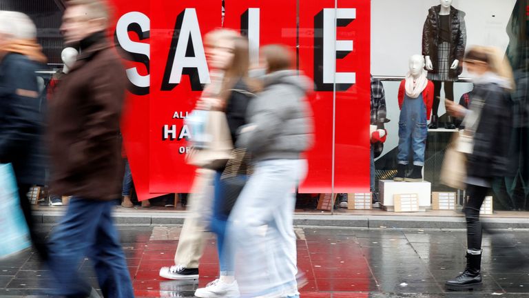 People walk past a sale sign in a clothing shop as people look for bargains in the traditional Boxing Day sales in Liverpool, Britain, December 26 , 2021. REUTERS/Phil Noble
