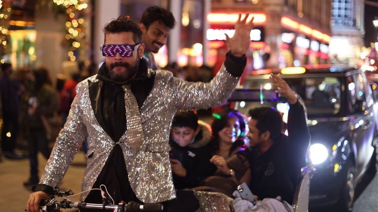 Seorang pria berpakaian rapi naik taksi roda tiga di pusat kota London menjelang perayaan Tahun Baru