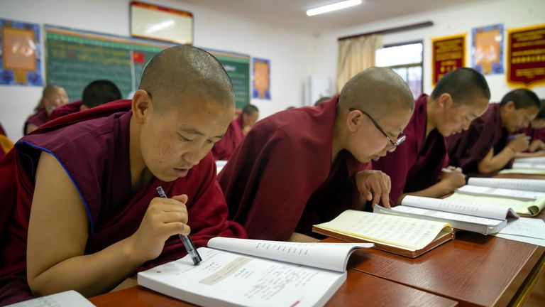 Tibetan Buddhist nuns read from their textbooks as they attend a Chinese language learning class. Pic: AP