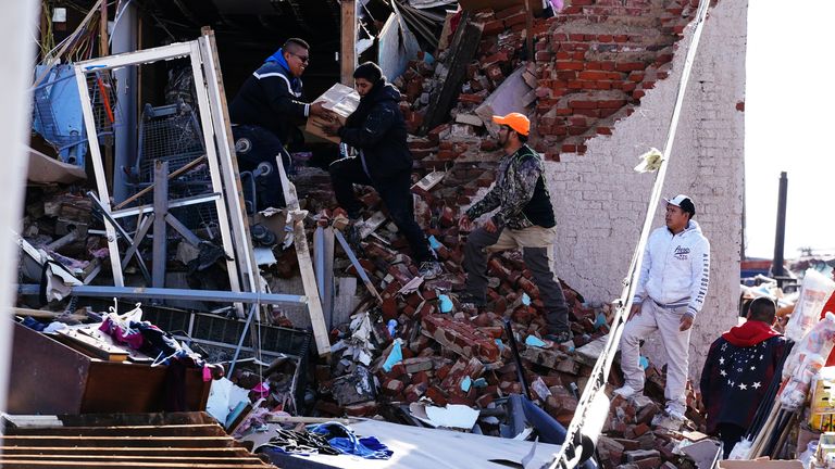 People carry out a box among the debris in Mayfield, Kentucky. Pic: AP