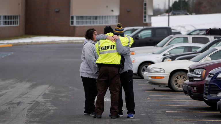 An Oakland County Sheriff...s deputy hugs family members of a student in the parking lot of Oxford High School in Oxford, Mich., Wednesday, Dec. 1, 2021. Authorities say a 15-year-old sophomore opened fire at Oxford High School, killing four students and wounding seven other people Tuesday. (AP Photo/Paul Sancya)