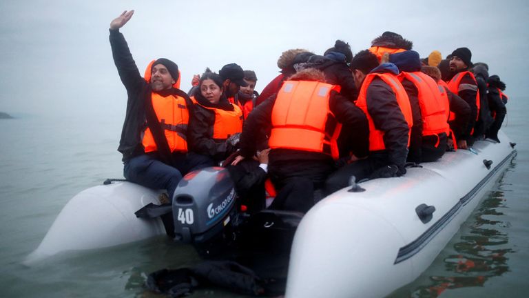 A group of migrants react as they succeeded to get on an inflatable dinghy, to leave the coast of northern France and to cross the English Channel, in Wimereux near Calais, France, December 16, 2021. REUTERS/Stephane Mahe
